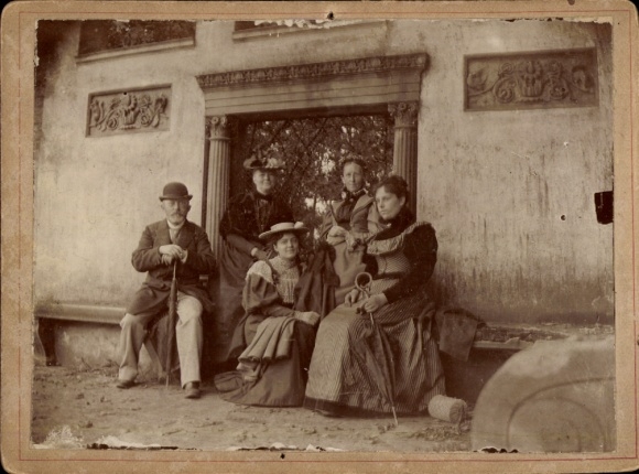 Photo group photo, women and man in front of a stone gate