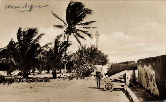 Photo Postcard Mozambique, man standing at cannon, palm trees
