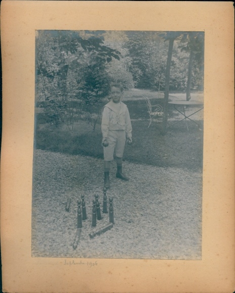 Photo of a boy bowling, child portrait with wheelbarrow and spade
