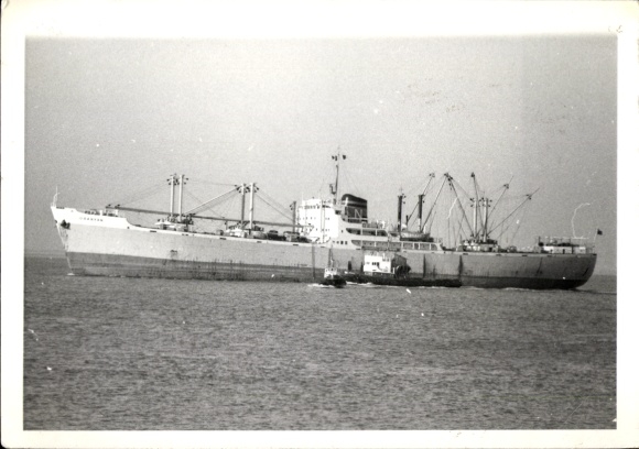 Photo of a cargo ship at sea, tugboat